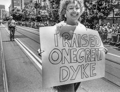 a woman holding a sign that says i raised one great dyke on the street