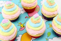 there are many cupcakes with frosting on the top one is pink, yellow and blue