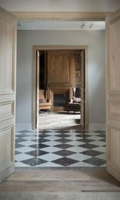 an open door leading to a living room with checkered flooring and wooden furniture