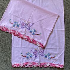 two pink bedspreads with butterfly appliques on them sitting on the floor