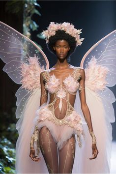 a woman in a bodysuit with wings and flowers on her head is walking down the runway