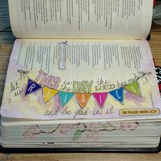 an open book on a wooden table with a cross and bunting banner in the middle