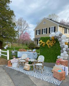 an outdoor party set up with balloons and presents on the ground in front of a house