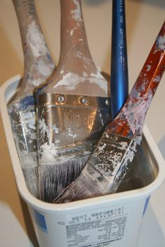 two paintbrushes in a bucket with some shavings on it's sides