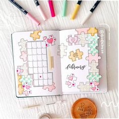 an open planner with colorful puzzles on it next to some pens and a penny