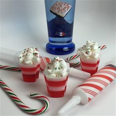 four cupcakes with white frosting and candy canes next to a bottle of vodka