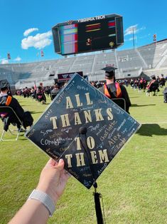 someone is holding up a graduation cap that says all thanks to them on the field