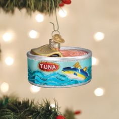 a tin can ornament hanging from a christmas tree with lights in the background