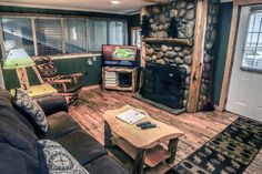 a living room filled with furniture and a fire place next to a wooden floored wall