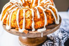 a bundt cake with icing drizzled over it on a wooden platter