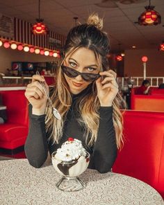 a woman sitting at a table with some food in front of her eyeglasses