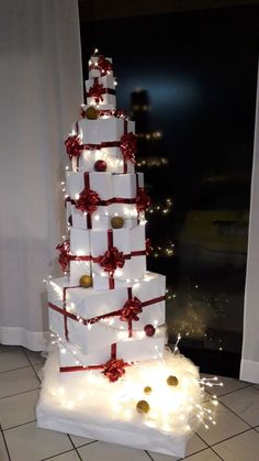 a christmas tree made out of white boxes with red bows and lights on it's sides