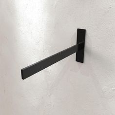 a close up of a black metal object on a white wall with no one around it