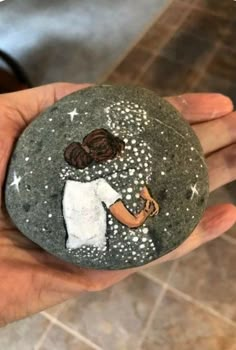 a hand holding a rock with a painting on it