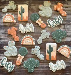 many decorated cookies are on a wooden table with cactuses and other desert themed items