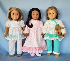 three dolls standing next to each other in front of a blue background with one holding a teddy bear