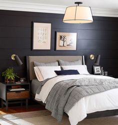 a bedroom with black walls, white bedding and two framed pictures on the wall