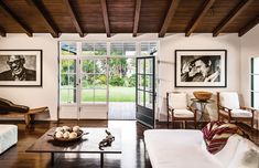 a living room filled with furniture and pictures on the wall next to a doorway that leads to a patio