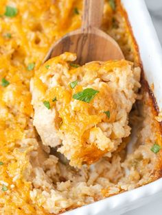 a casserole dish with chicken and rice in it, topped with a wooden spoon