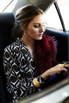 a woman sitting in the back seat of a car looking down at her cell phone