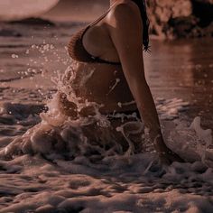 a woman in a bathing suit splashes water onto the beach