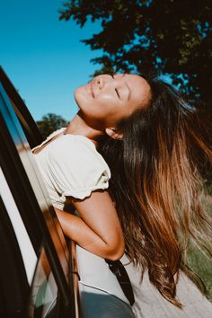 a woman leaning out the window of a car with her head hanging out the window