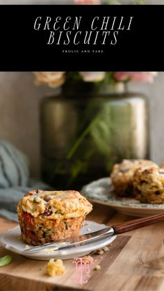 two muffins sitting on top of a wooden cutting board next to a knife and fork