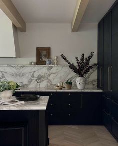 a kitchen with marble counter tops and black cabinets