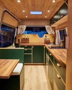 the interior of a camper with wood flooring and green cabinets