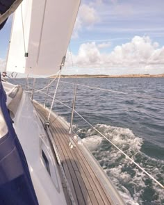 there is a sailboat sailing on the water in the day time and blue sky with white clouds