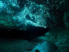 the inside of a cave filled with lots of green lights and water flowing through it