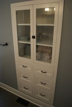 a white cabinet with glass doors and drawers