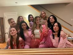 a group of women dressed in pajamas taking a selfie with their cell phone while posing for the camera