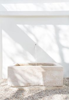 a water fountain in front of a white wall