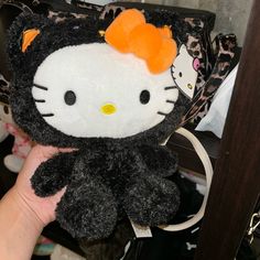 a hello kitty purse with an orange bow on it's head is being held by a hand