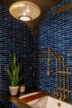 a bathroom with blue tiles and a white bathtub next to a potted plant