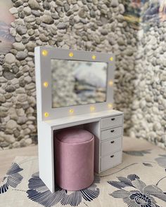 a small vanity with a mirror and stool in front of a rock wallpapered background