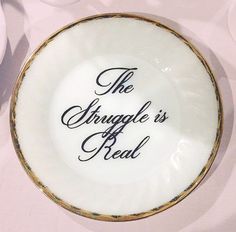 the struggle is real on a white plate with gold trimmings and black lettering