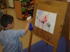 a young boy is painting on an easel