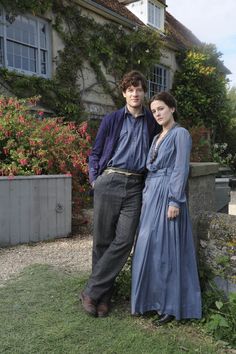 a man and woman standing next to each other in front of a house