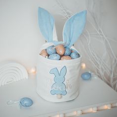 a white bucket filled with chocolate eggs and bunny ears sitting on top of a table