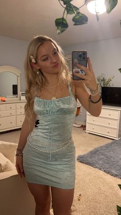 a woman is taking a selfie in her bedroom wearing a blue dress and heels