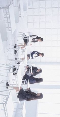 four people sitting on chairs in a room with white walls and flooring, all looking up at the ceiling