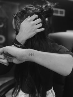 a woman with a tattoo on her arm holding another person's hand while sitting in a car