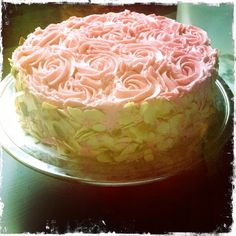 a cake with pink frosting and roses on it sitting on a glass platter