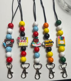 four different colored beads are attached to lanyards on a white table with black cord