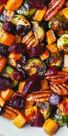 a white plate topped with brussel sprouts and sweet potatoes covered in cranberry sauce