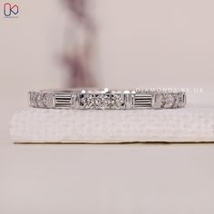 a white gold diamond ring sitting on top of a towel