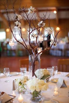 the centerpieces are arranged in vases with flowers and candles on the table