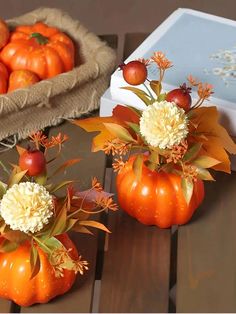 two pumpkins with flowers in them sitting on a table